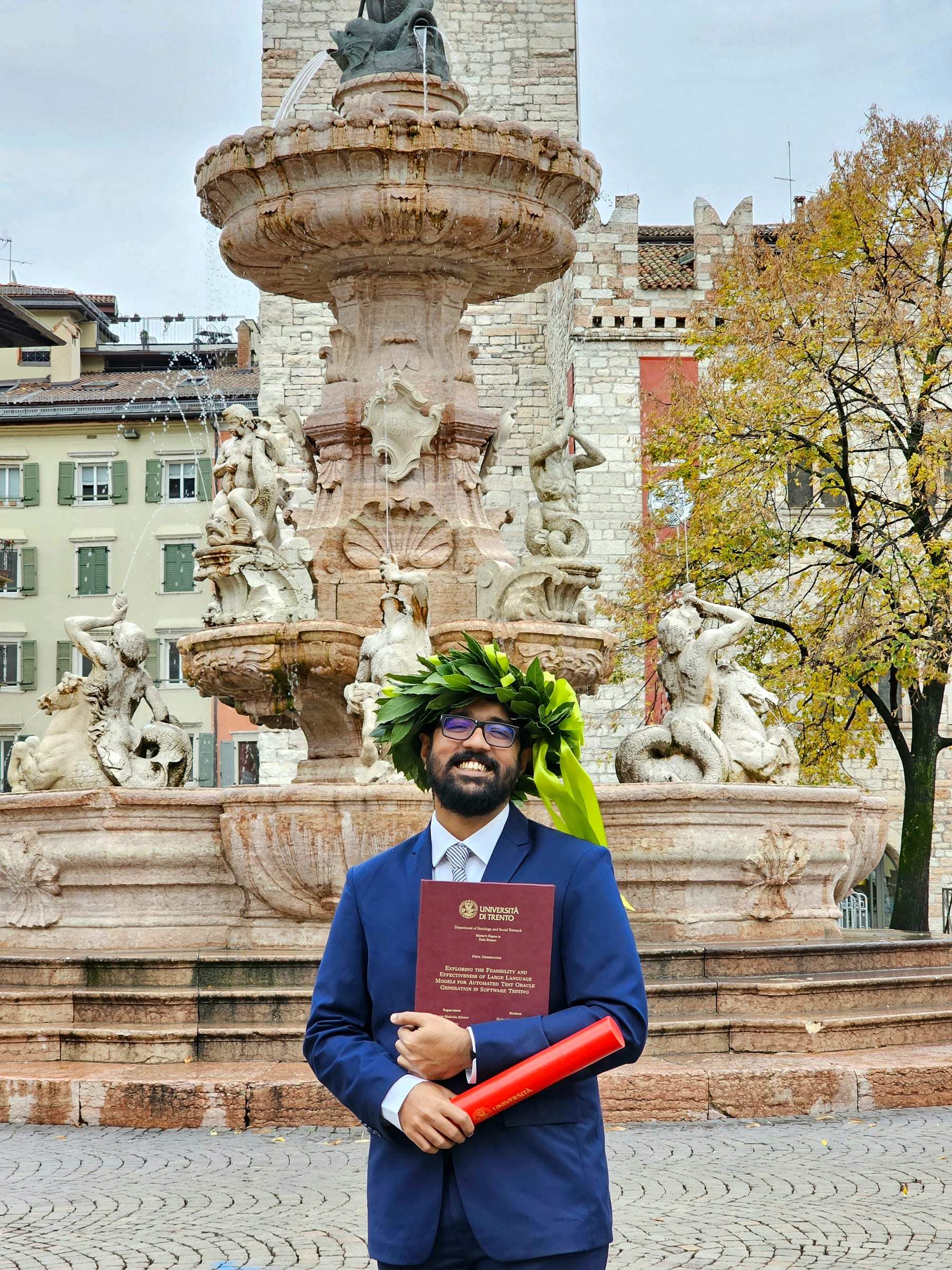 Shaker Mahmud Khandaker at his graduation from the University of Trento, holding the bound thesis and a red diploma tube.